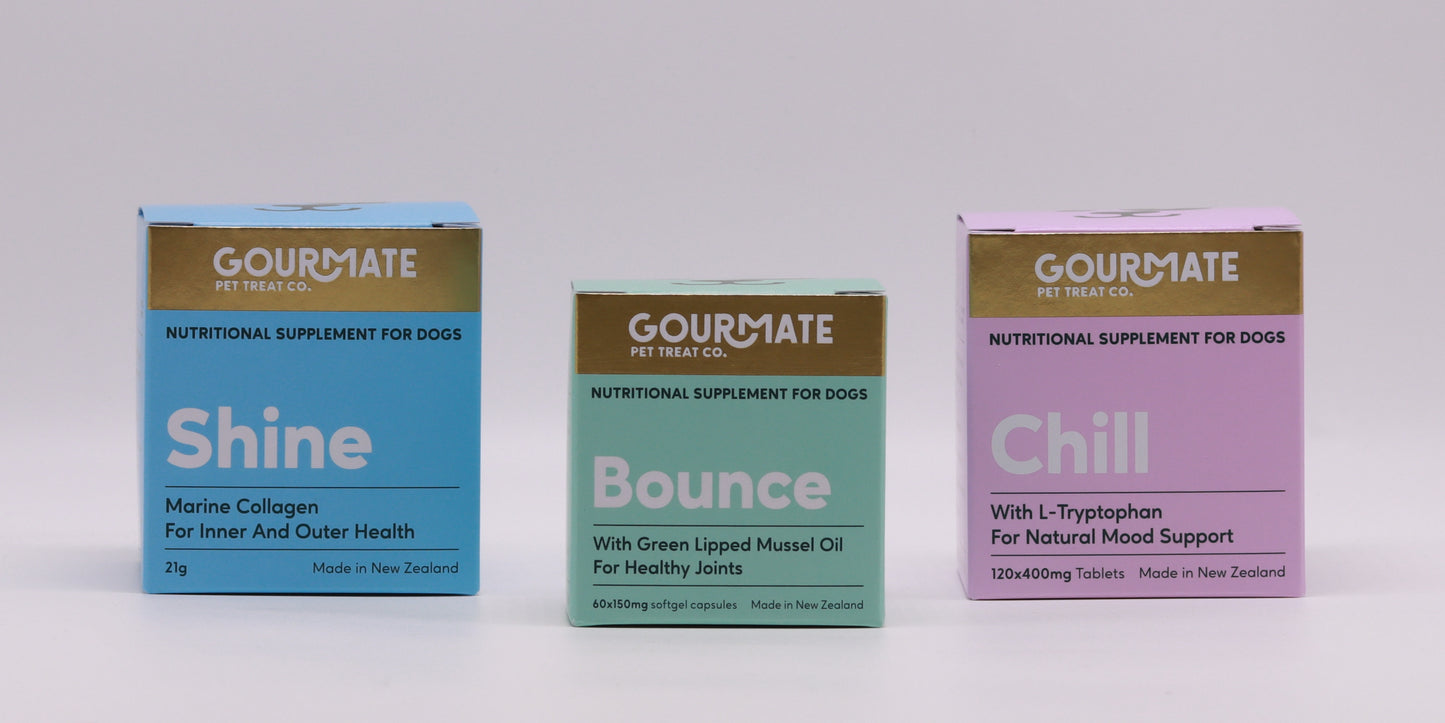 Displayed are three boxes of New Zealand-made dog supplements from Gourmate Pet Treat Co.: "Shine Marine Collagen" for skin health, "Bounce" for joint support, and "Chill" for mood enhancement, each crafted to ensure comprehensive canine well-being.