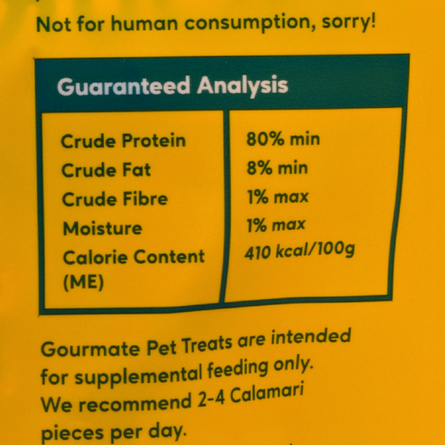 Gourmate Pet Treat Co. Wild Caught Calamari's yellow label displays a guaranteed analysis, including protein, fat, fiber, and moisture percentages. Enhanced with omega-3s via freeze-drying from Wild Caught Calamari, it's ideal for pets only—strictly not for humans.