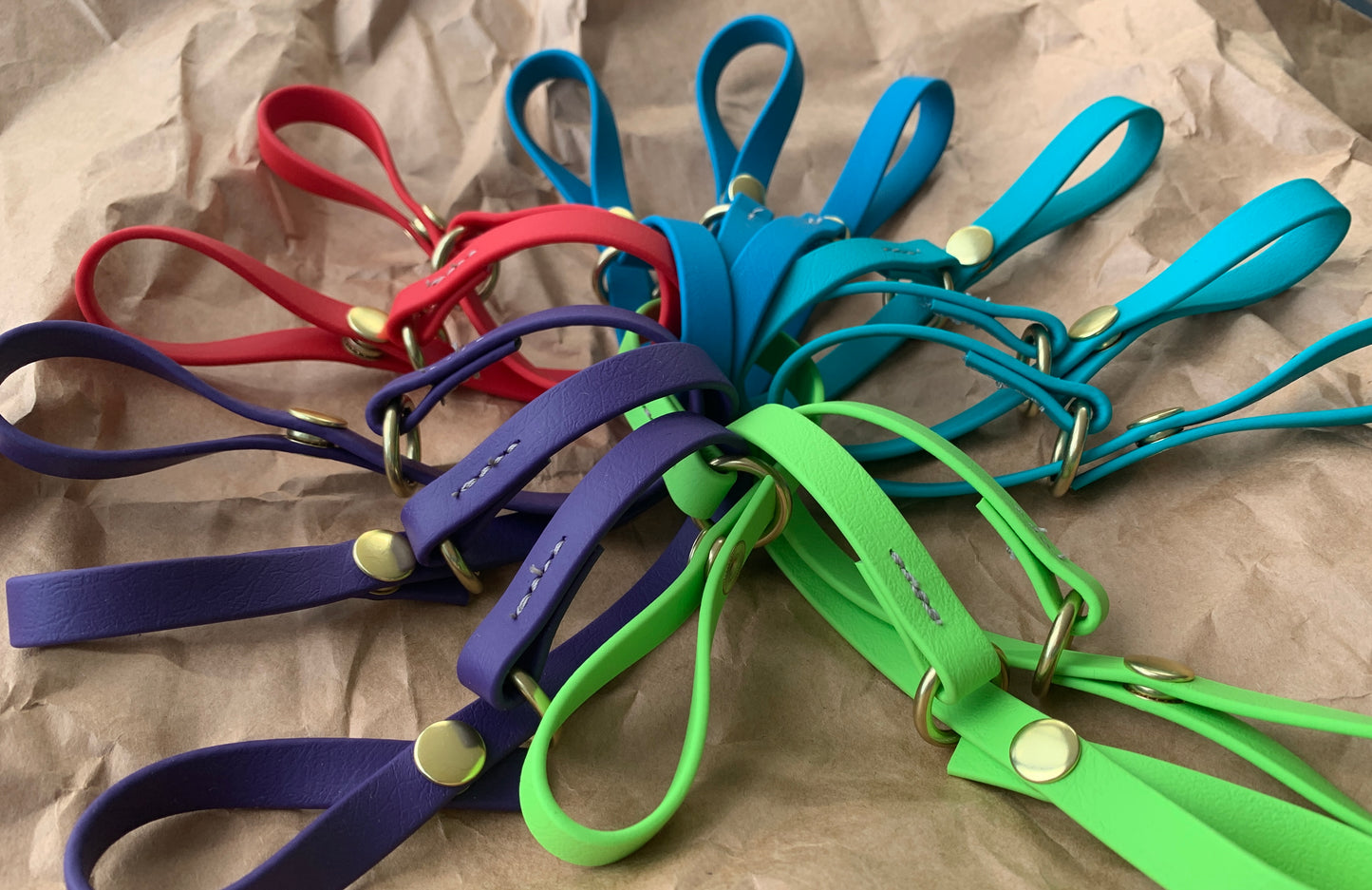 Colorful leather loops with metal studs, perfect to attach to your belt, arranged on crinkled paper. Trailblazing Tails: The Long Line Holder by Your Whole Dog.