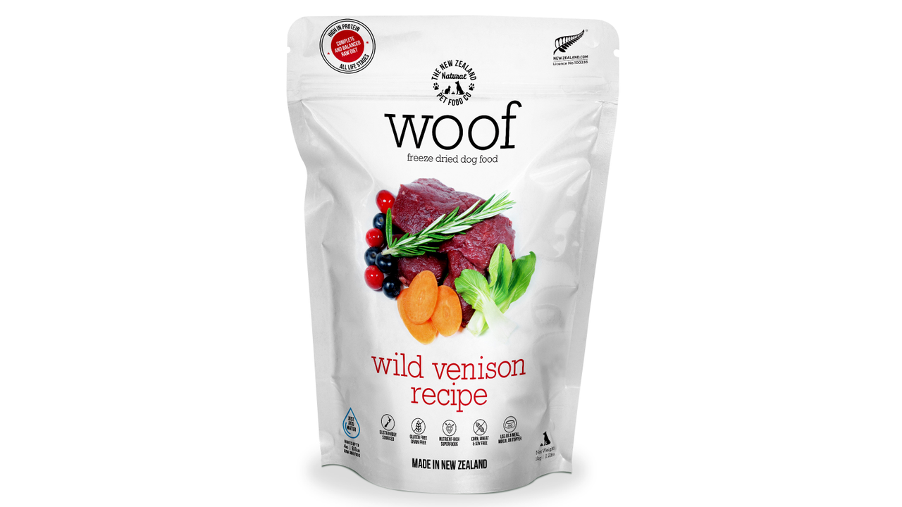 A white bag of WOOF Freeze Dried Wild Venison Dog Food by WOOF - The NZ Natural Petfood Co, showing venison, carrots, leafy greens, and herbs on the front.
