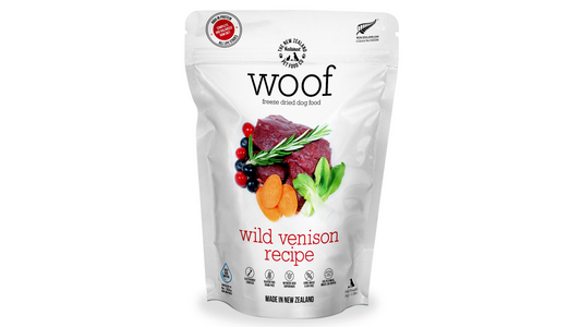 A white bag of WOOF Freeze Dried Wild Venison Dog Food by WOOF - The NZ Natural Petfood Co, showing venison, carrots, leafy greens, and herbs on the front.
