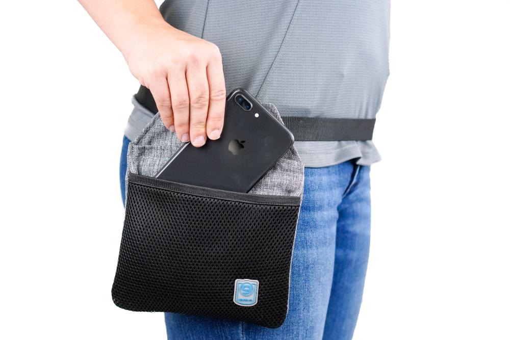 Someone carefully places a smartphone into the Blue-9 INSPIRE Training Treat Pouch, featuring a secure snap-back closure to attach to their waist—ideal for holding essentials on the go.