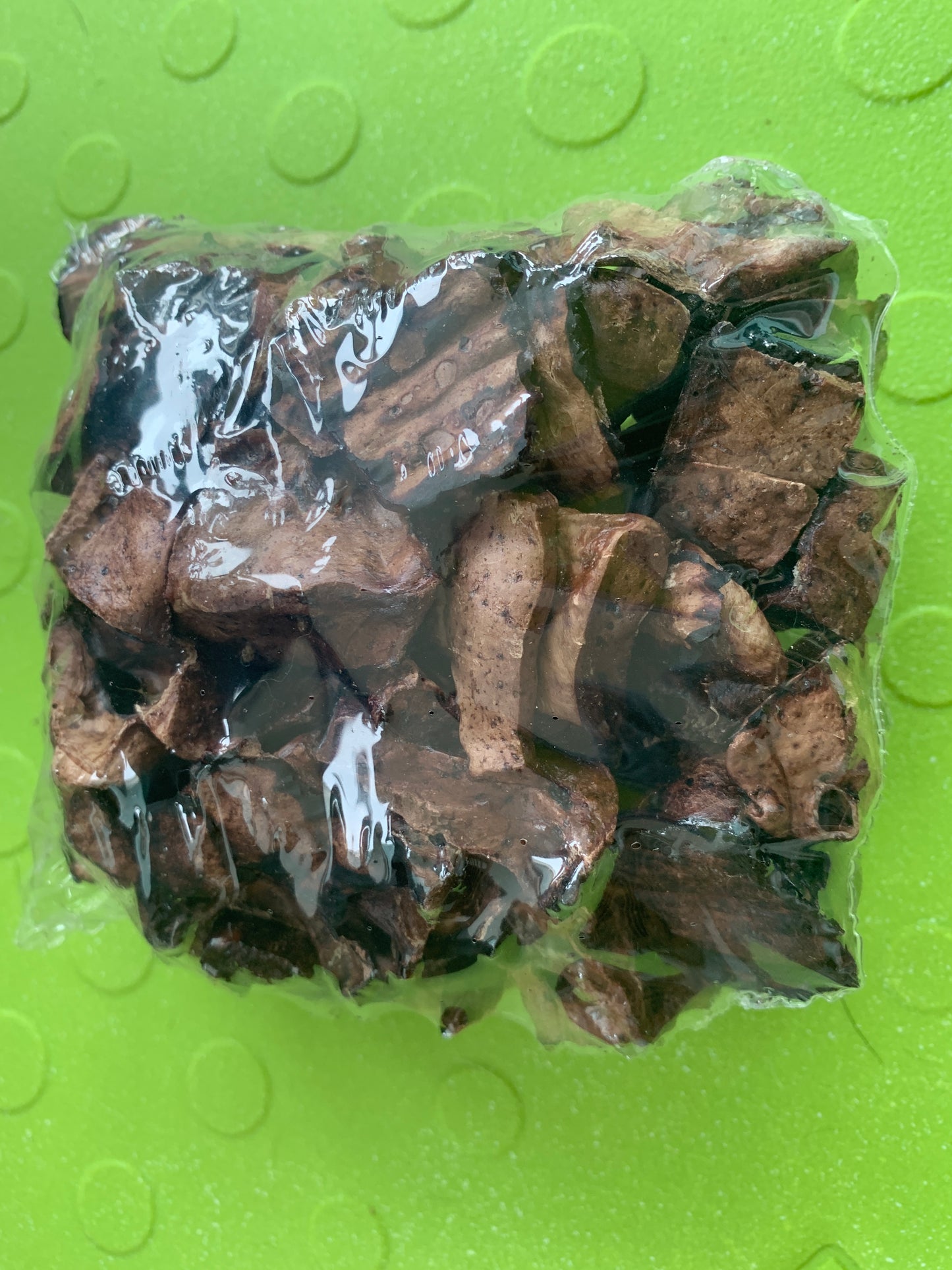 A sealed plastic bag of Superior Pet Food Co. Ranchmans Lamb Marshmallow Bites, featuring dried brown mushrooms and air-dried lamb lung, rests on a green textured surface.