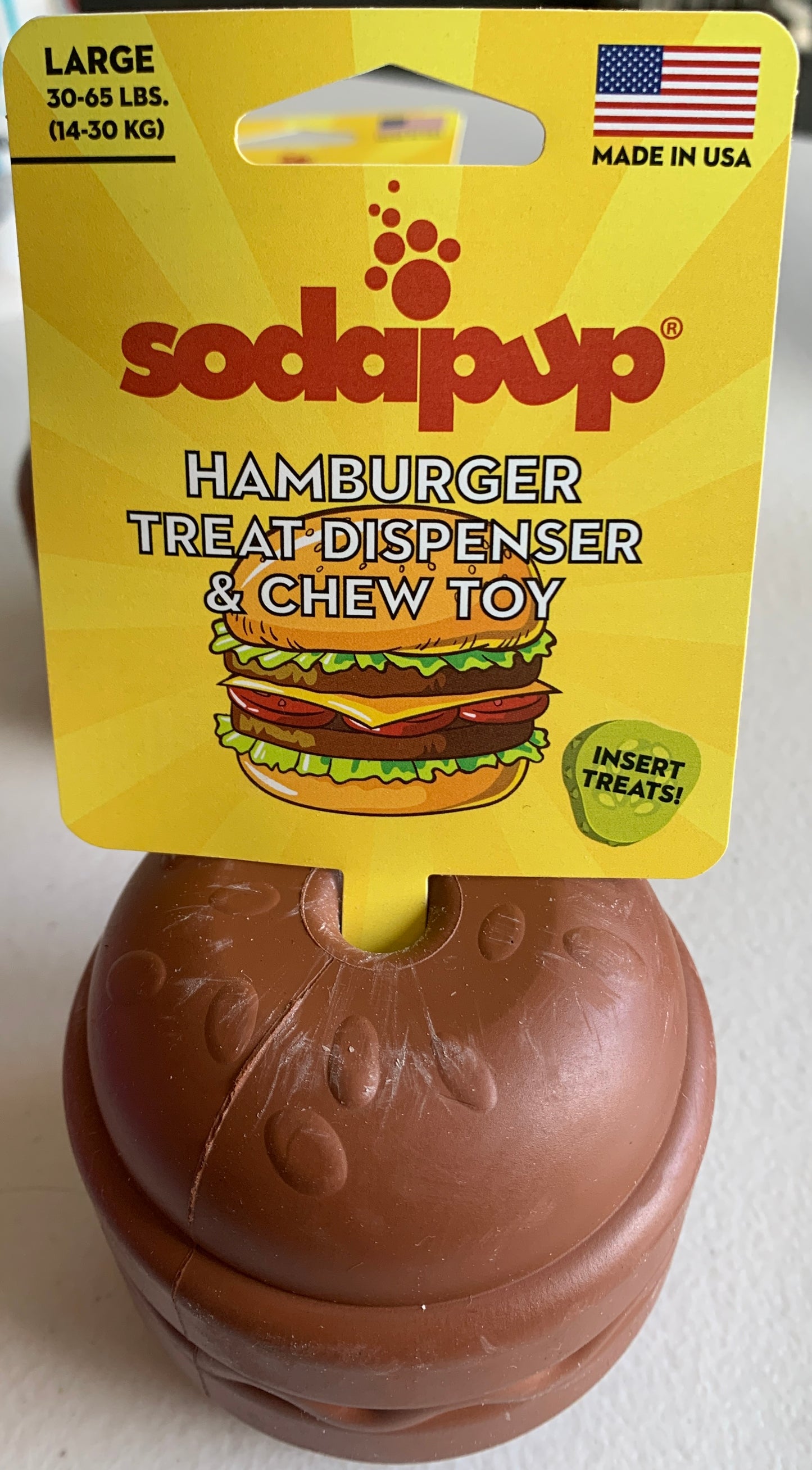 The $10 CLEARANCE Soda Pup HAMBURGER Chew Toy & Treat Dispenser by Your Whole Dog is a brown, hamburger-shaped toy for large dogs, made in the USA. It dispenses treats and encourages interactive enrichment play.