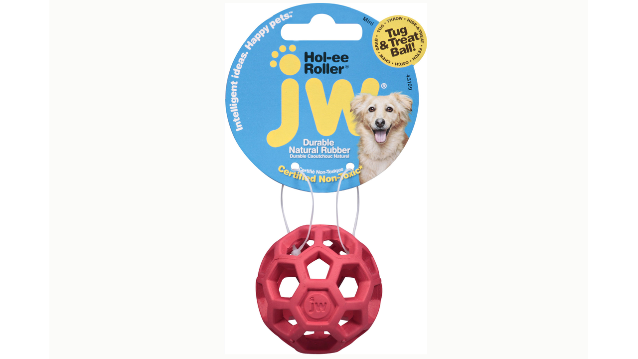This JW Hol-ee Roller dog toy, crafted from durable natural rubber in a vibrant red with a hexagonal design, is displayed on a blue and yellow packaging card featuring a dog's image and brand information of Your Whole Dog, making it an outstanding product choice among Hol-ee Rollers.