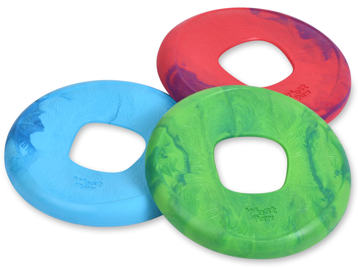 Three West Paw Sailz dog frisbees, in red, blue, and green with a square center hole, are displayed on a flat surface. Crafted from durable Seaflex material by West Paw, these grooved discs ensure endless outdoor fun.