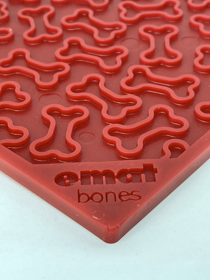 A close-up of a red Your Whole Dog Soda Pup EMAT ENRICHMENT LICKING MAT with bone-shaped cavities, labeled "smart bones.