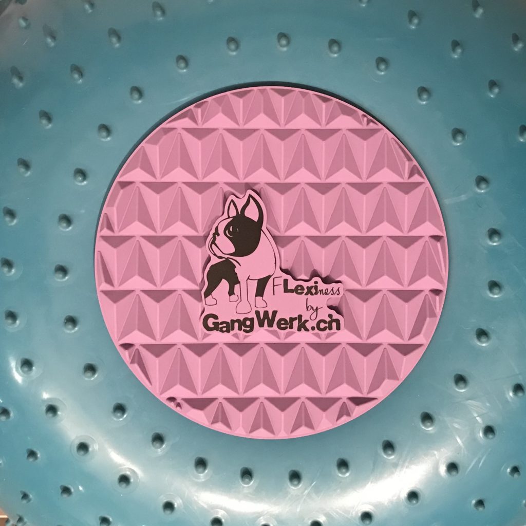 Close-up of a textured blue Flexiness SensiTarget with a circular pink center, ideal for tactile stimulation. It features a Boston Terrier graphic and the text "Your Whole Dog," making it perfect as a paw target for enhancing your pet's perception.