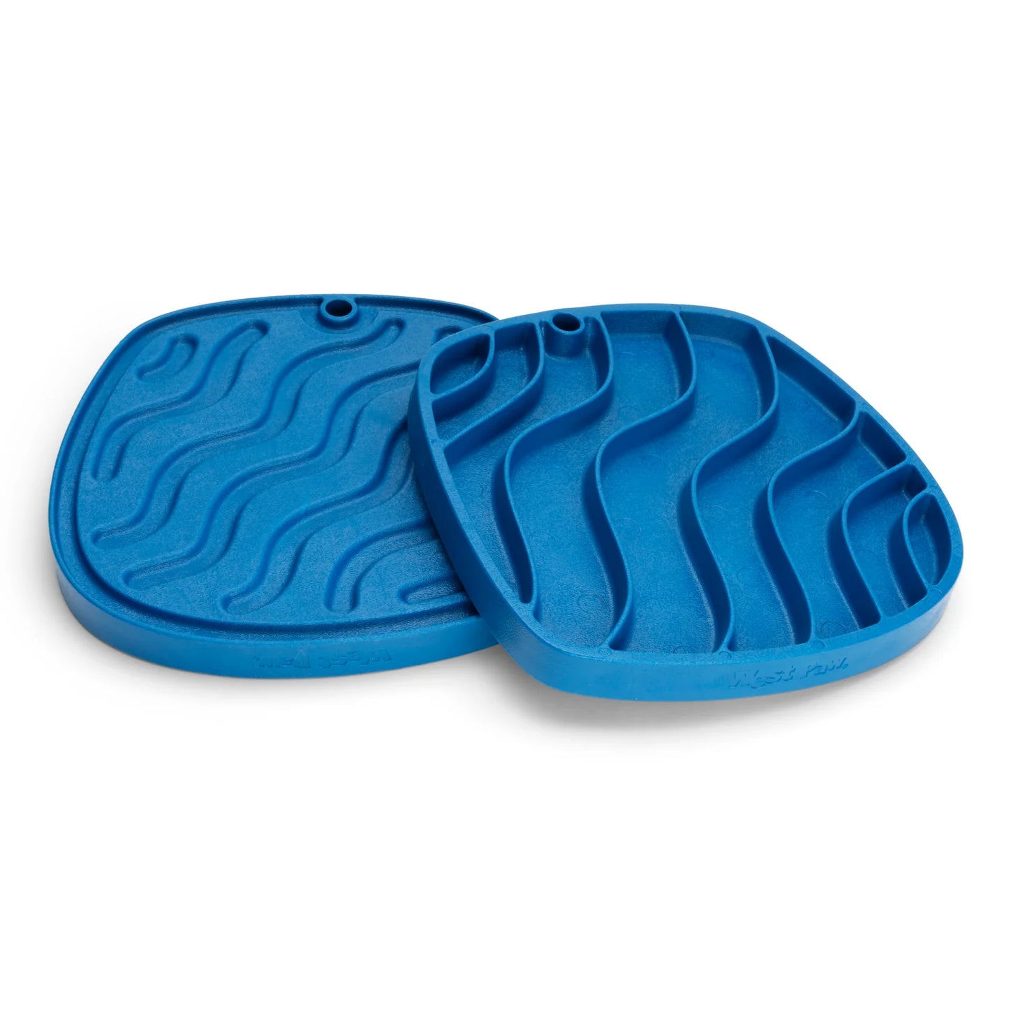 Two blue, square-shaped West Paw Feast Mats with wavy patterns are shown. Available from Your Whole Dog, these slow feeders feature grooves for spreading treats and are made from recycled ocean-bound plastic.