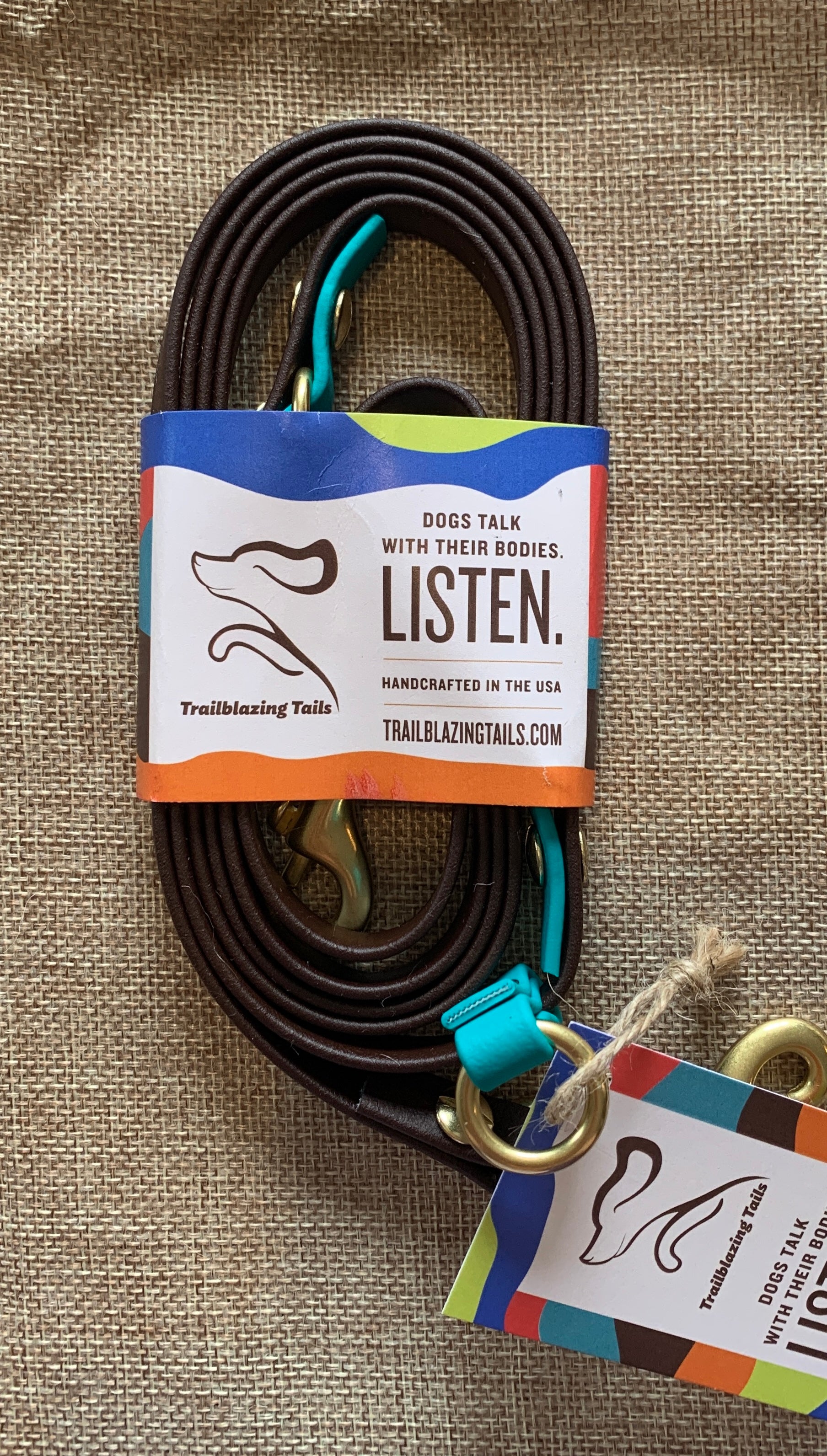 A multifunctional dog leash, Trailblazing Tails: The Sunny, with an adjustable length and a tag that says listen from the brand Your Whole Dog.