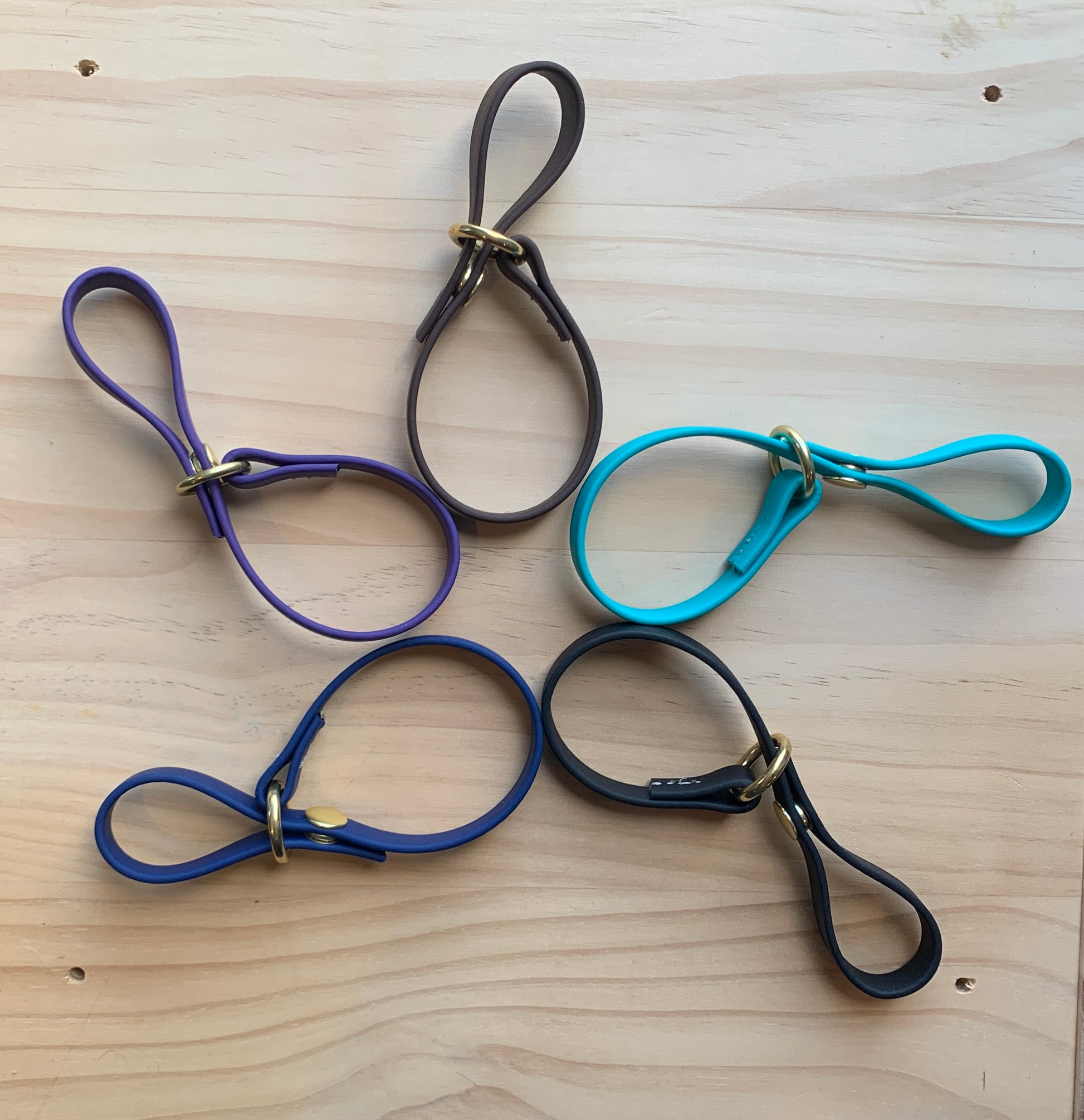 Four different colored Trailblazing Tails: The Long Line Holder leashes, featuring a long line holder and snap closure, beautifully displayed on a wooden table.