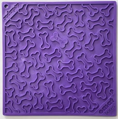 A purple silicone mat featuring a bone pattern and the words "lick me!" in the center. The brand name "Your Whole Dog" is printed in the corner, making it a perfect addition for dog health and enrichment mats.