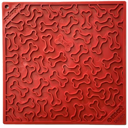 Red pet lick mat with bone-shaped grooves, perfect for enrichment and promoting dog health. Small center section labeled "lick me." Brand name "Your Whole Dog" printed in the corners.