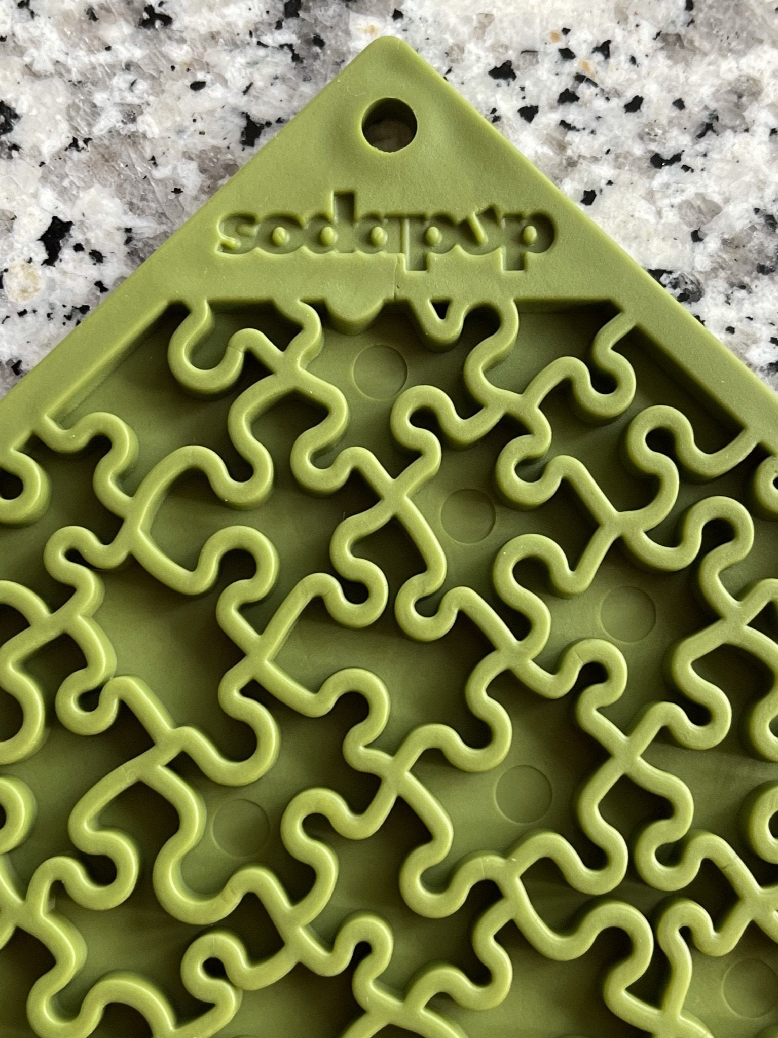 A close-up view of a green 'Your Whole Dog' branded Soda Pup EMAT ENRICHMENT LICKING MAT with an intricate maze-like texture.